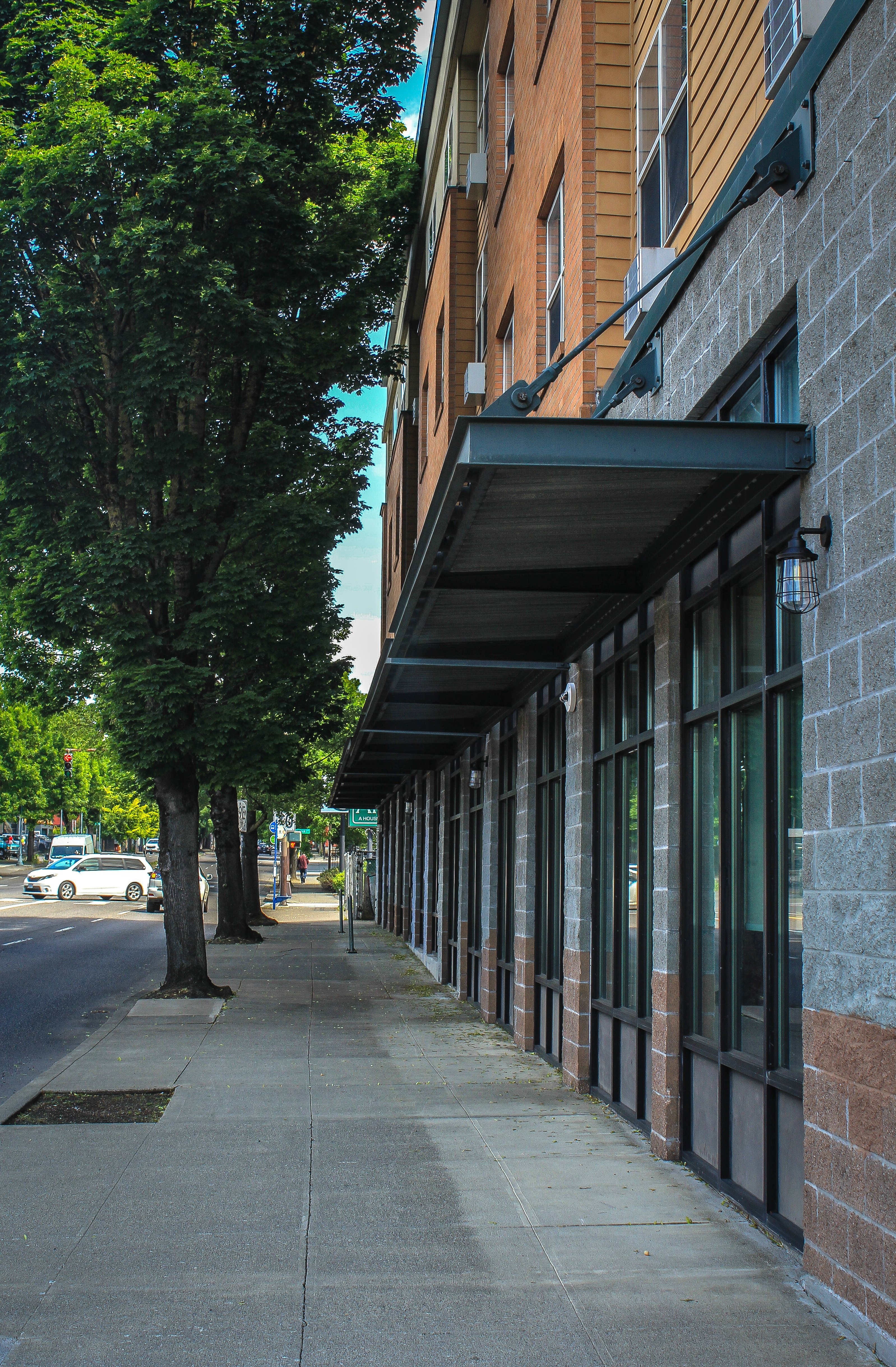 A long building with a black awning sits on a sidewalk.